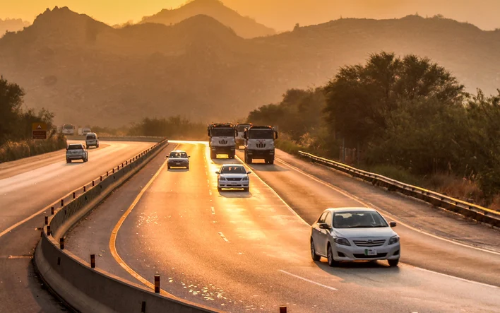 Cars driving on the M-2 motorway at sunset with the Salt Range hills in the background